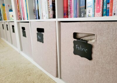 Crafts room cubby storage with labeled cubes and organized books on bookshelf